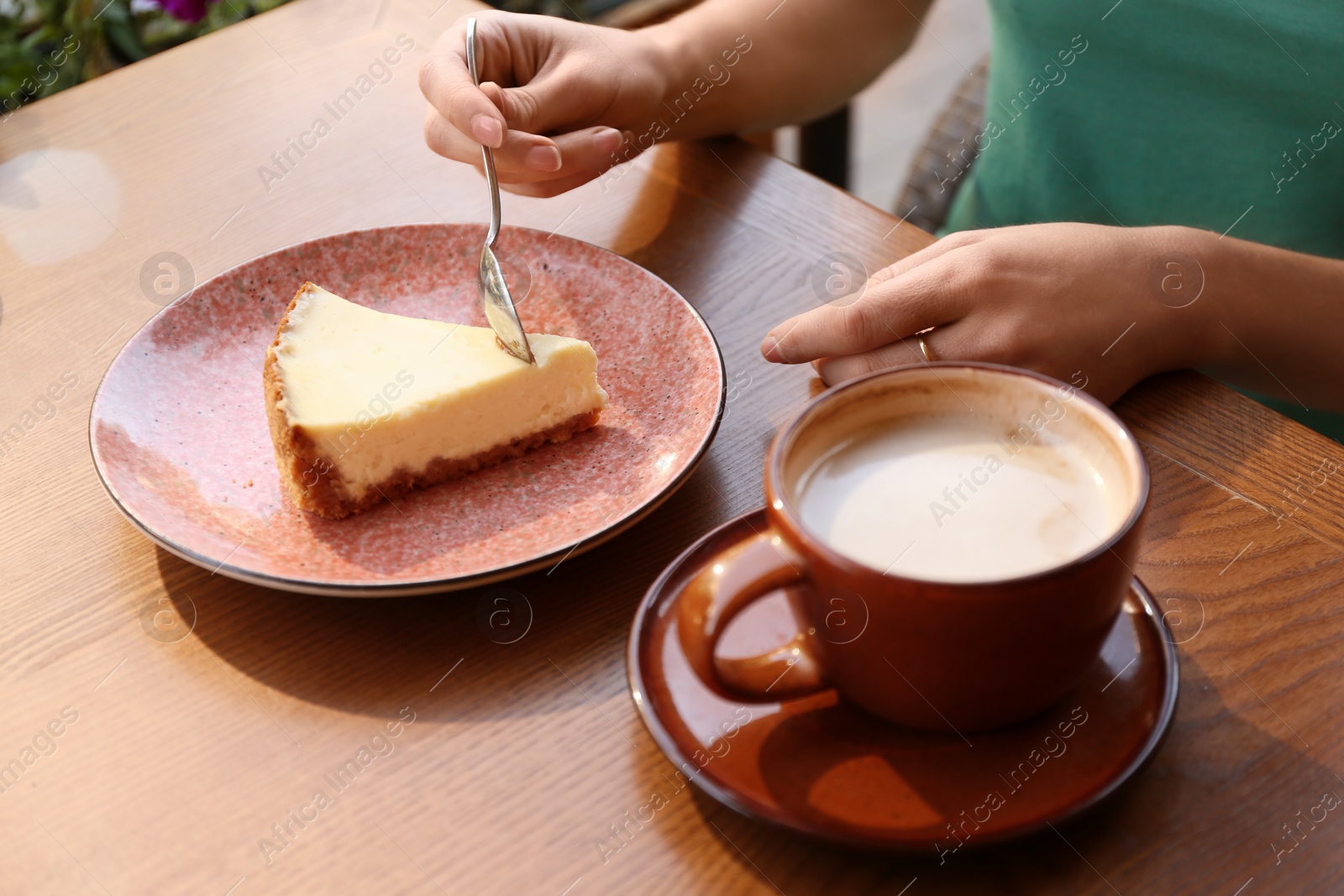 Photo of Woman eating slice of cheesecake at table, closeup