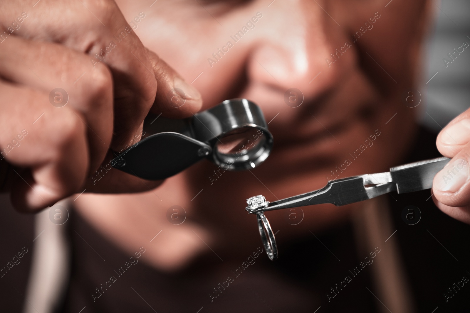 Photo of Professional jeweler evaluating beautiful ring, closeup view