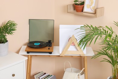 Photo of Stylish turntable with vinyl record on wooden table in cozy room