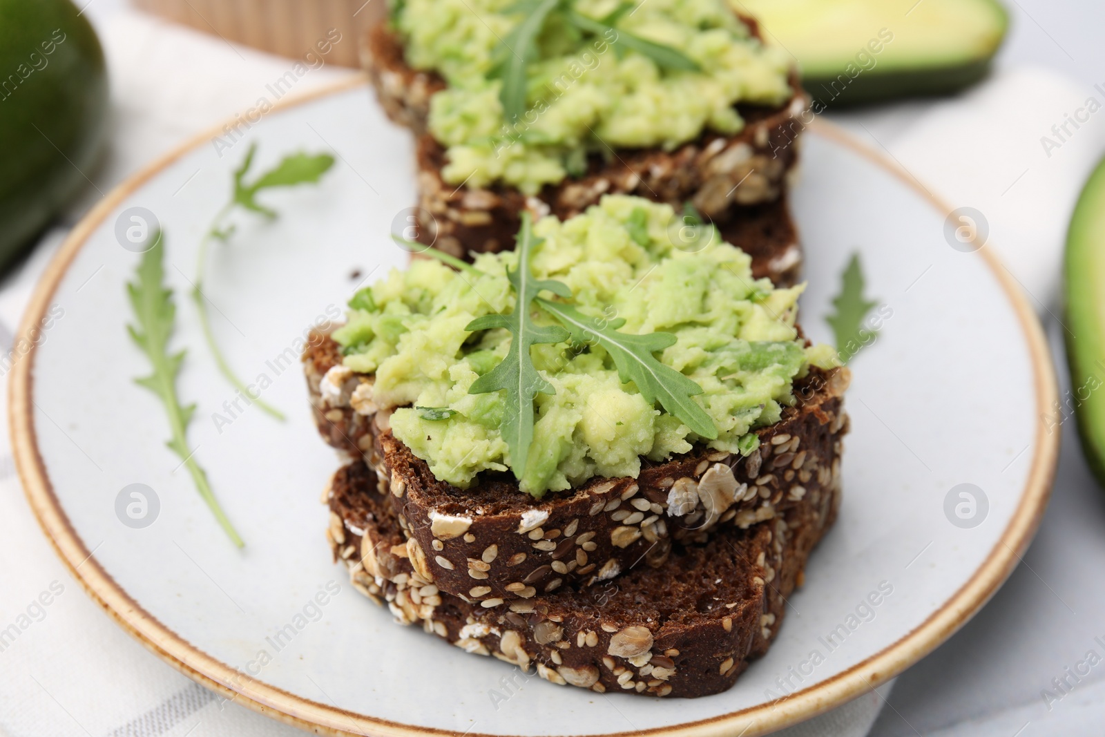 Photo of Delicious sandwiches with guacamole and arugula on plate, closeup