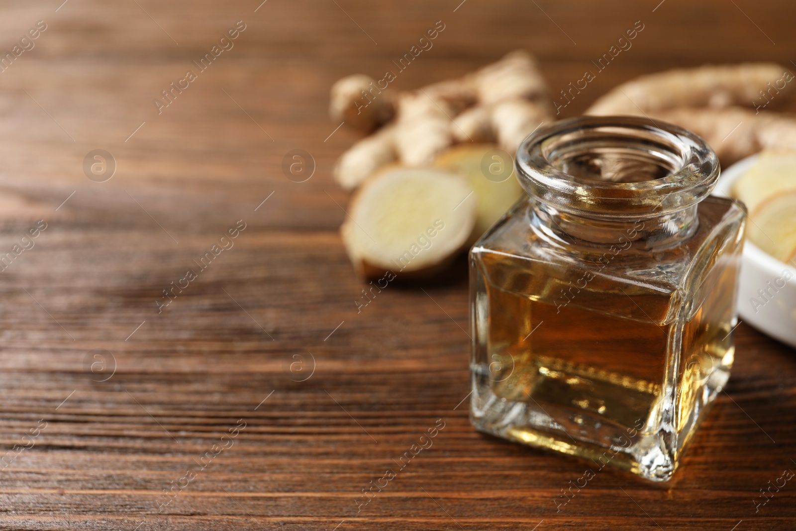 Photo of Ginger essential oil in bottle on wooden table. Space for text