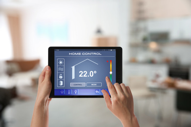 Image of Woman using tablet to set indoor temperature, closeup. Smart home automation system