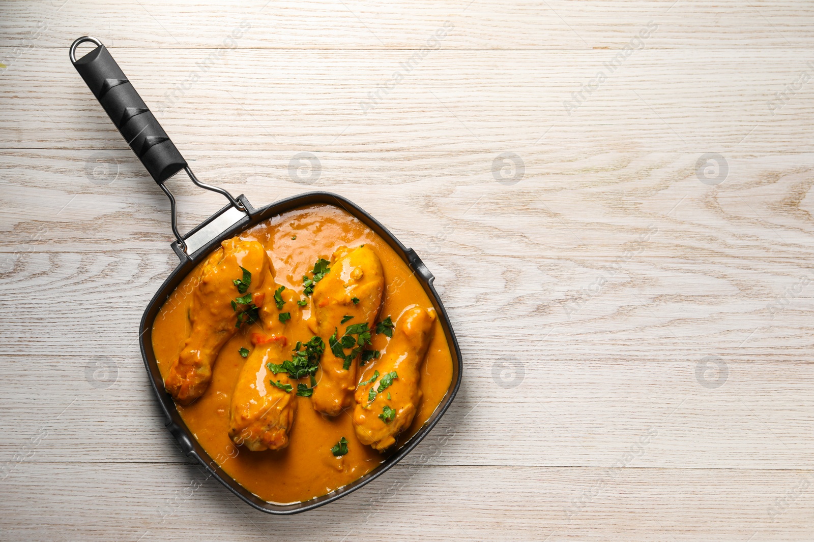 Photo of Tasty chicken curry with parsley on wooden table, top view. Space for text