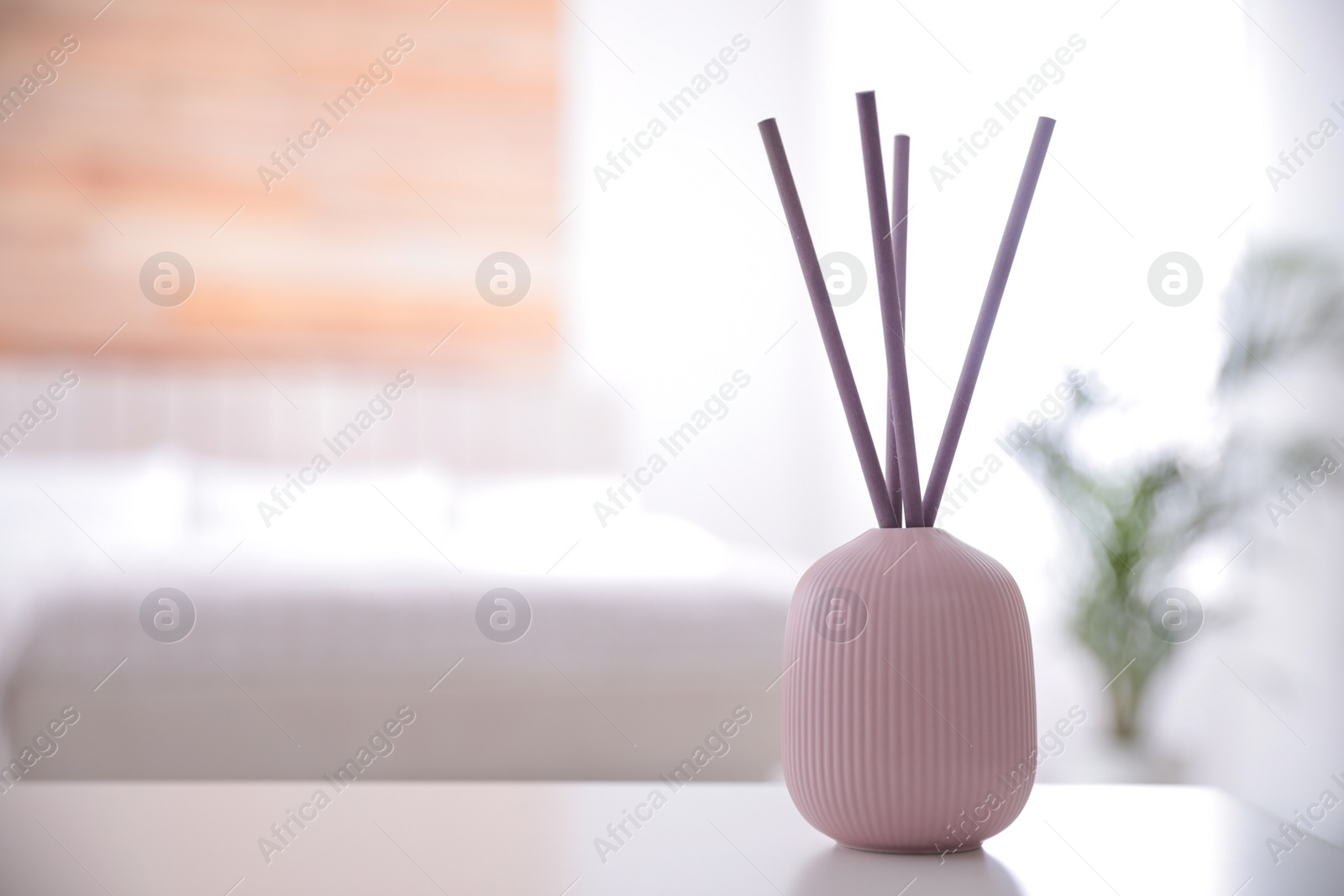 Photo of Reed air freshener on white table indoors. Space for text