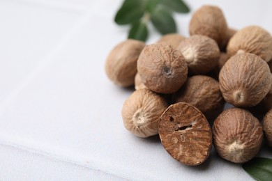 Photo of Heap of nutmegs on white table, closeup. Space for text