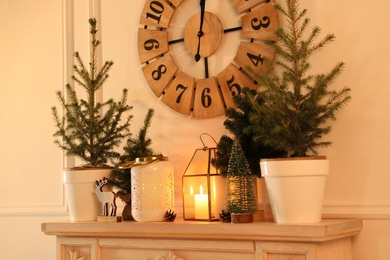 Photo of Small fir trees on mantelpiece indoors. Christmas interior design