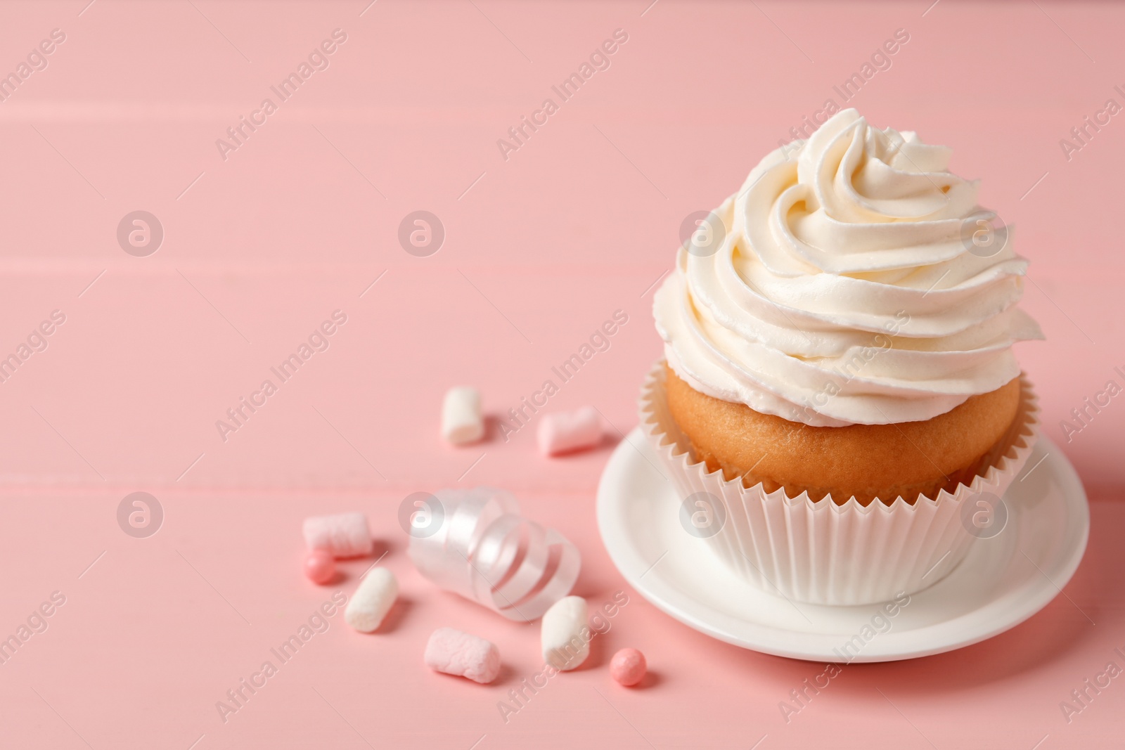 Photo of Delicious cupcake decorated with cream on pink background, space for text
