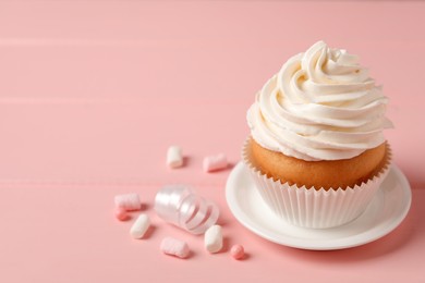 Delicious cupcake decorated with cream on pink background, space for text