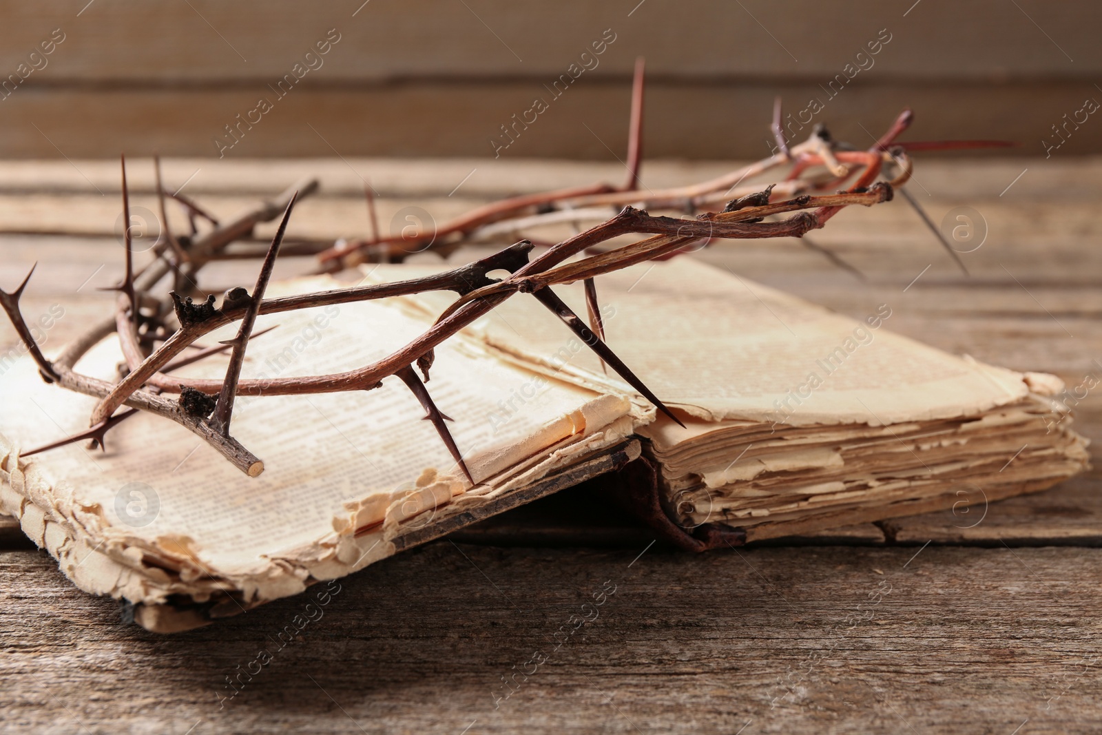 Photo of Crown of thorns and Bible on wooden table, closeup