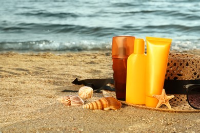 Sun protection products and beach accessories on sand near sea, space for text