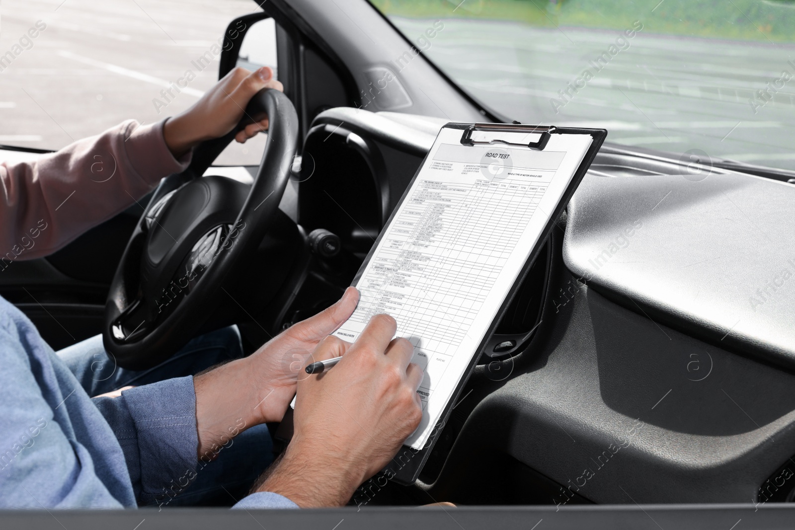 Photo of Driving school. Student passing driving test with examiner in car at parking lot, closeup