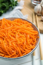 Photo of Delicious Korean carrot salad in bowl on white wooden table, closeup