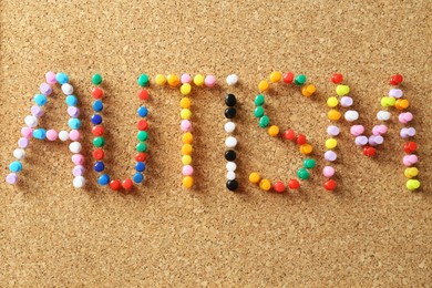 Word Autism made of colorful pins on cork board, closeup