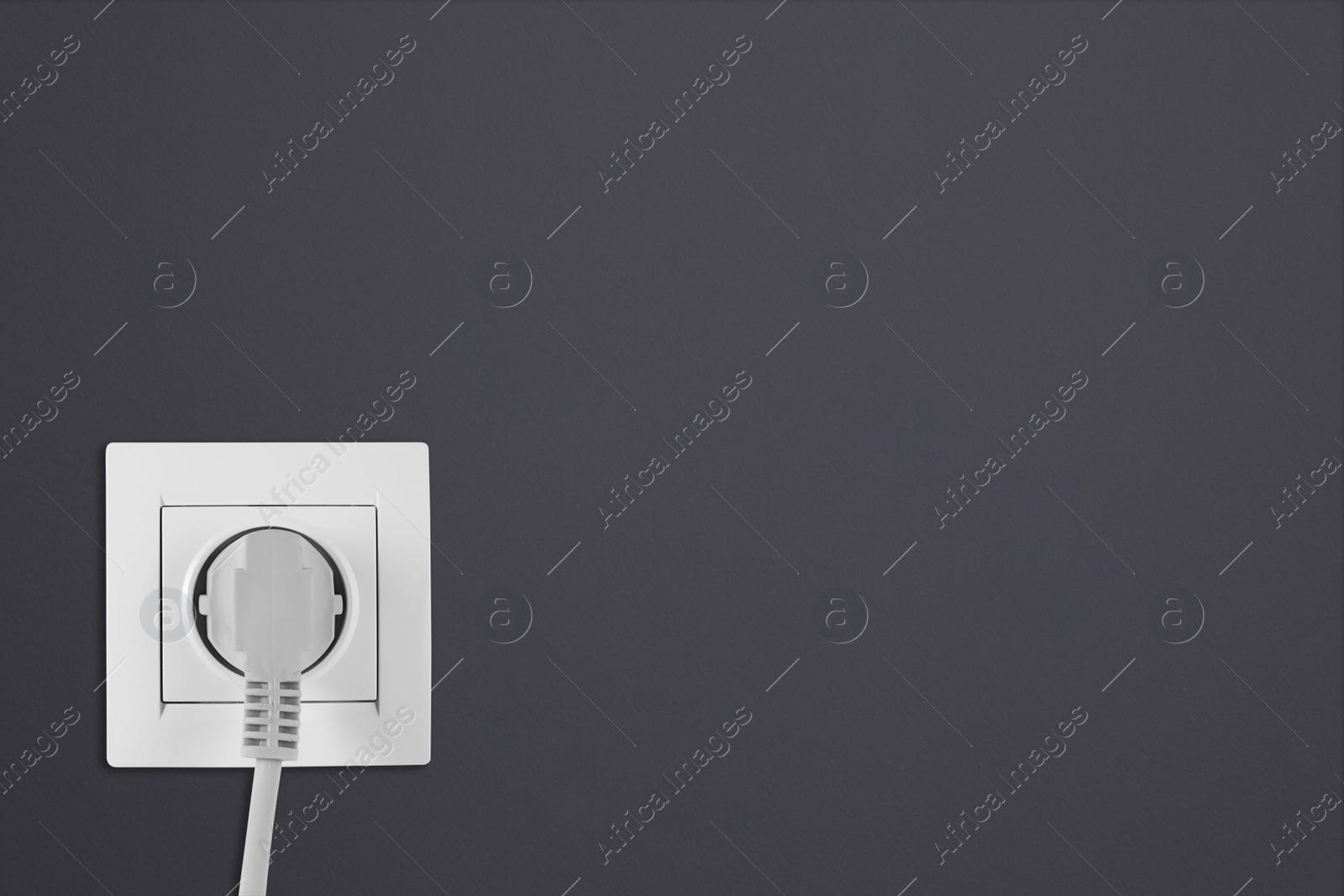 Dark grey wall with power socket and inserted plug, space for text. Electrical supply Image of Dark grey wall with power socket and inserted plug, space for text. Electrical supply