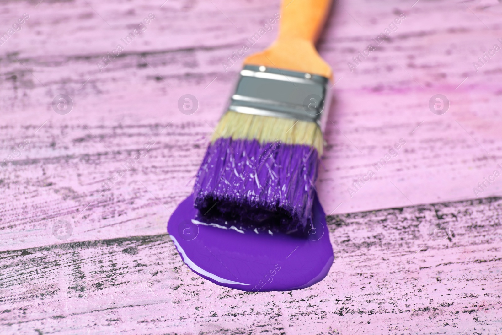 Photo of Paint stroke and brush on pink wooden table, closeup