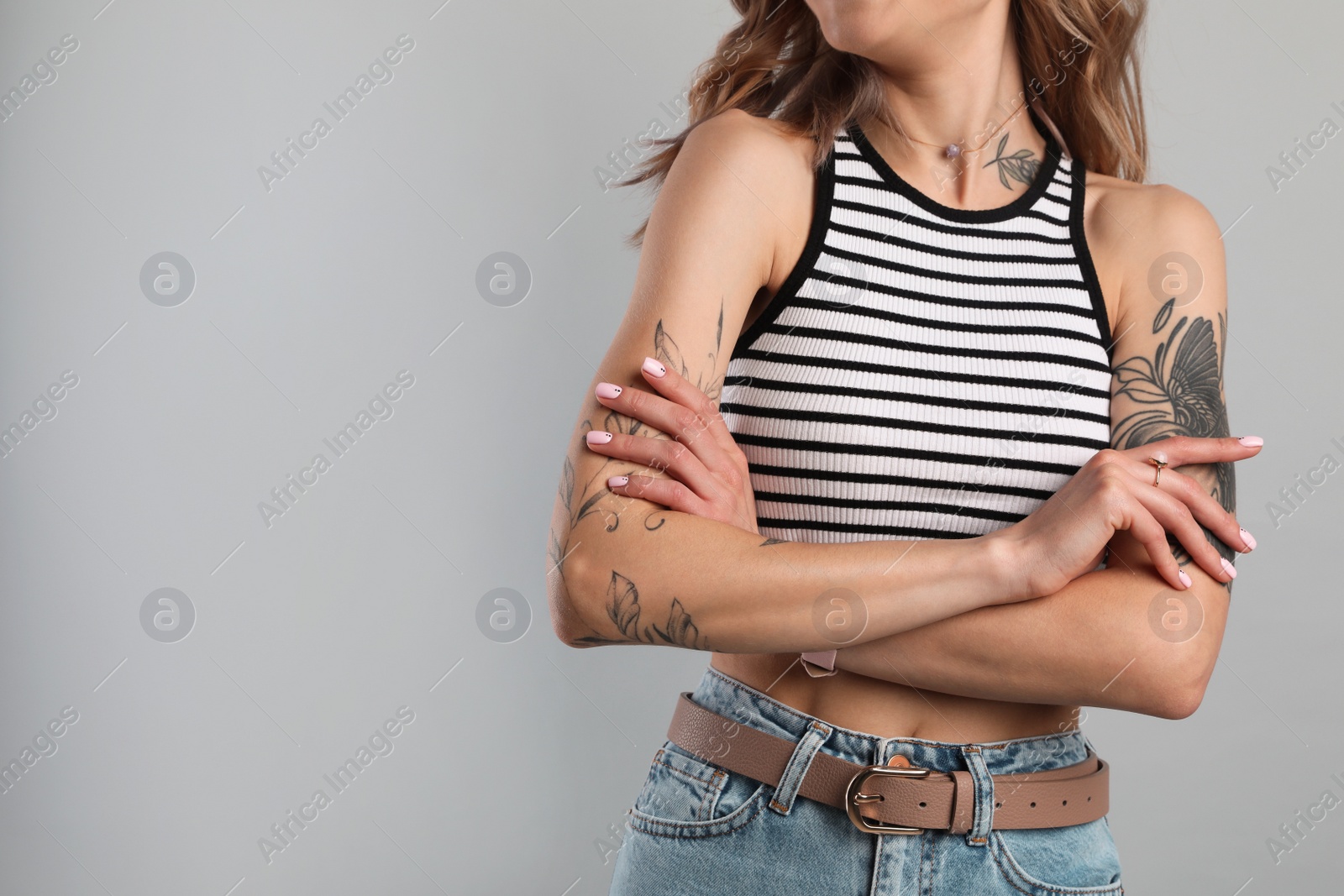 Photo of Beautiful woman with tattoos on body against grey background, closeup. Space for text