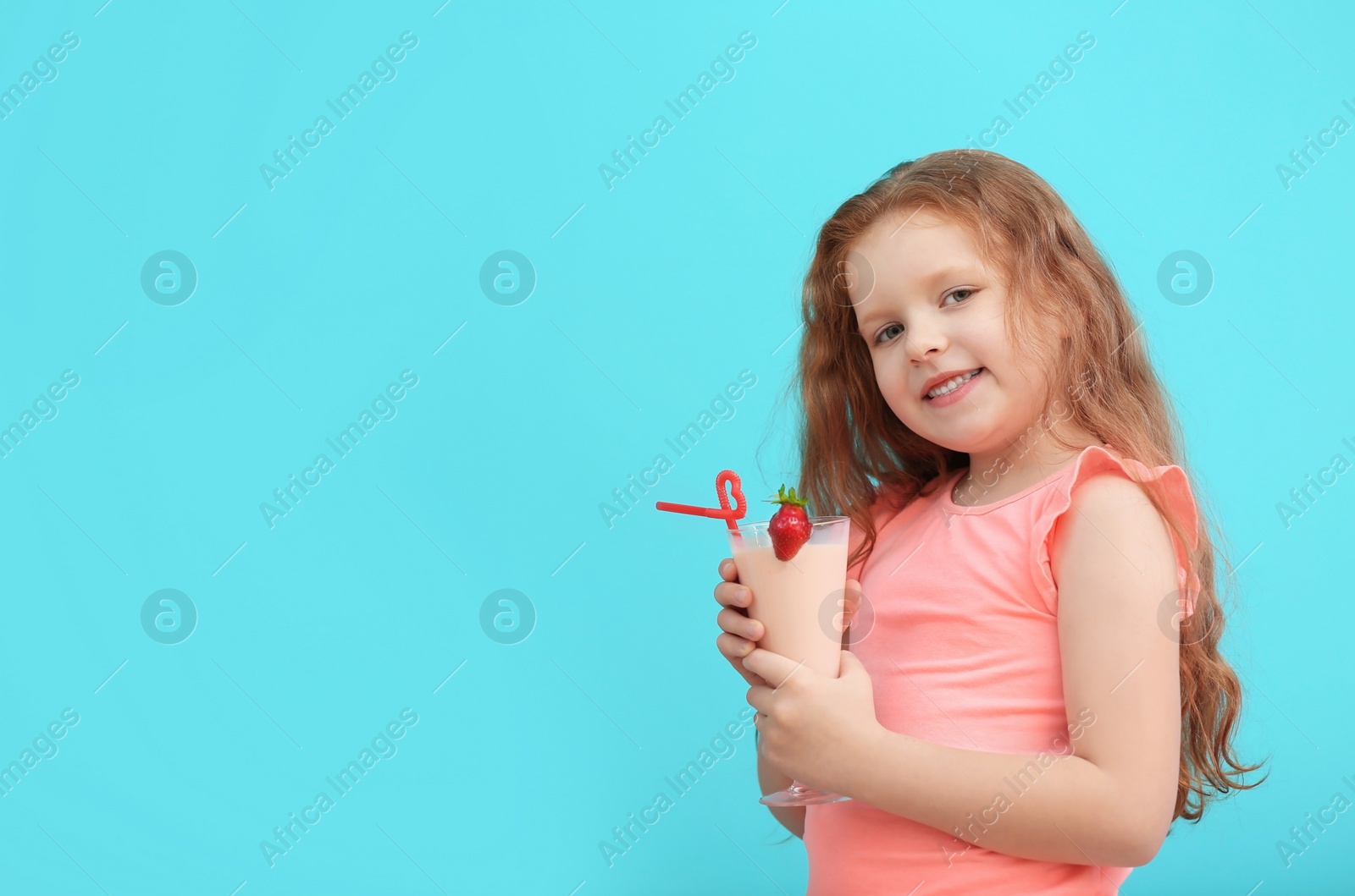 Photo of Little girl with glass of delicious milk shake on color background