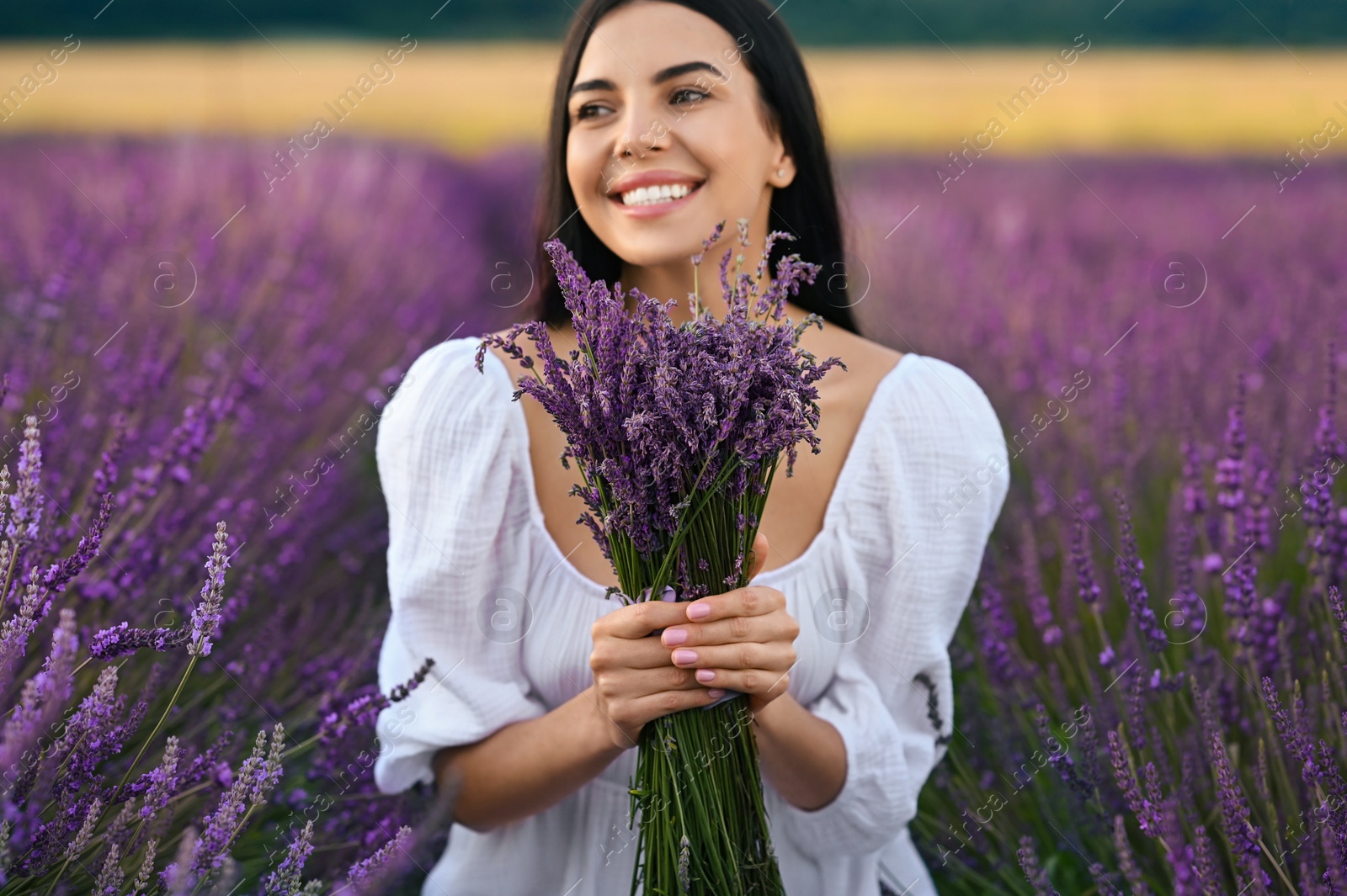 Photo of Beautiful young woman with bouquet in lavender field