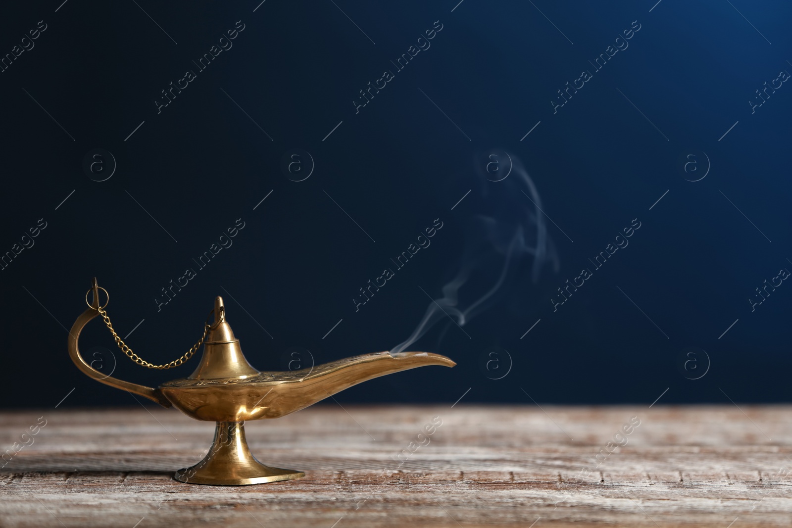 Photo of Aladdin lamp of wishes on wooden table against dark background