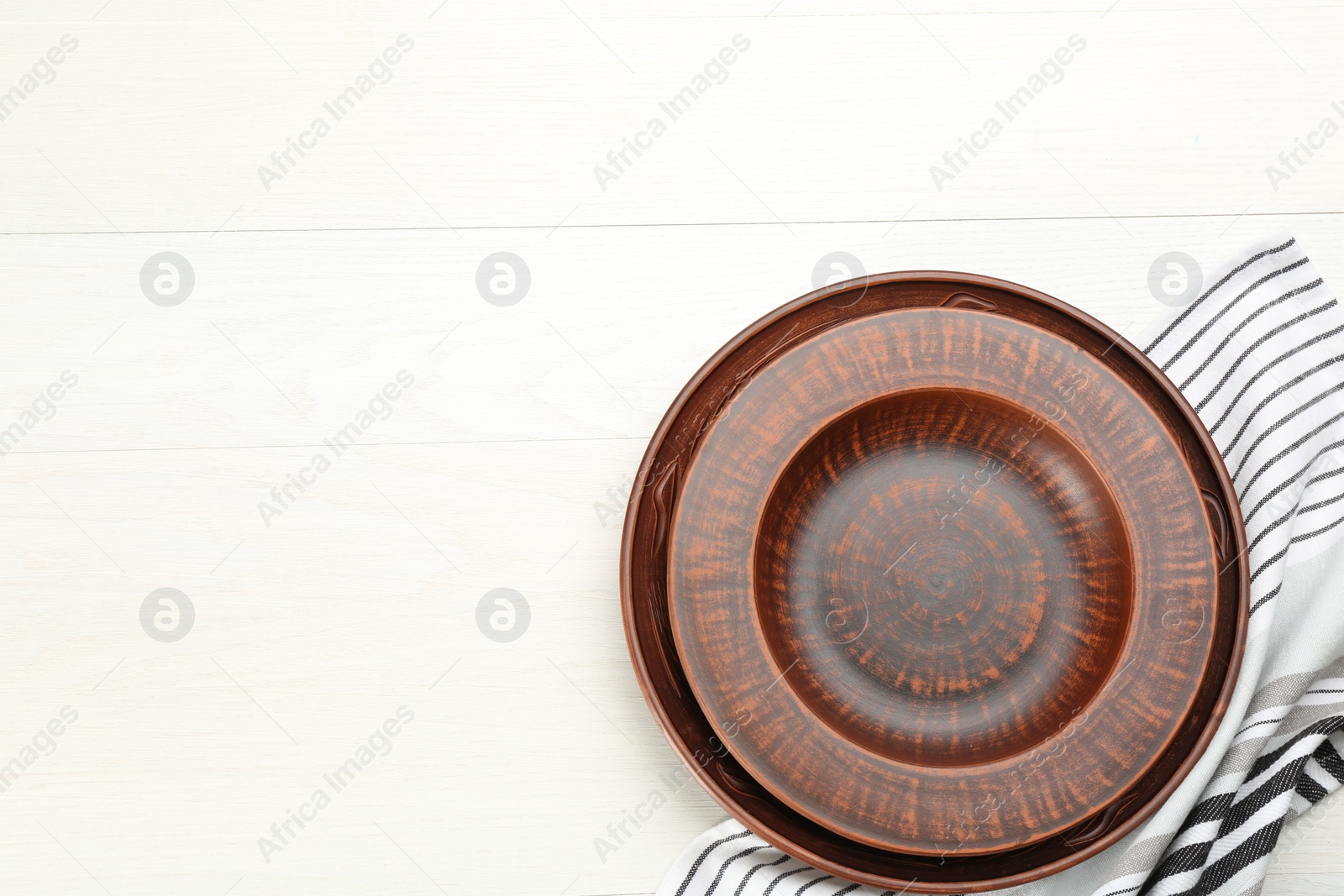 Photo of Clay plates on white wooden table, flat lay. Space for text