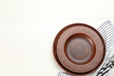 Clay plates on white wooden table, flat lay. Space for text