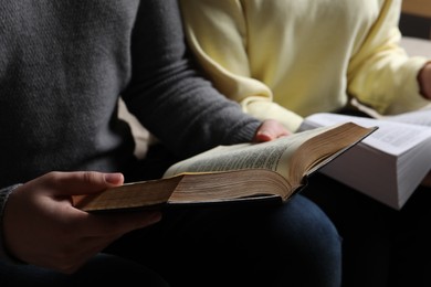 Photo of Couple sitting and reading holy Bibles, closeup