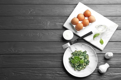 Photo of Tasty cooked spinach served on dark wooden table, flat lay with space for text. Healthy food