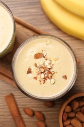 Photo of Tasty banana smoothie with almond and cinnamon on wooden table, flat lay