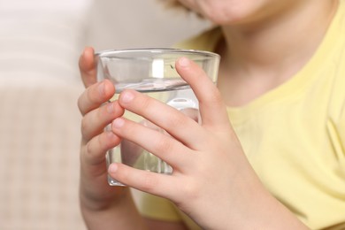 Photo of Little boy holding glass of fresh water, closeup