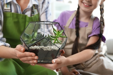 Photo of Mother and daughter taking care of plants at home, closeup