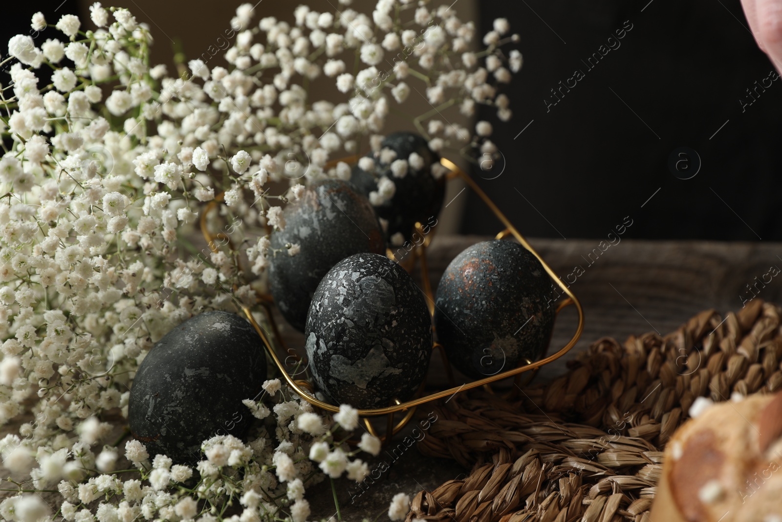 Photo of Decorated Easter eggs and flowers on wooden table, space for text