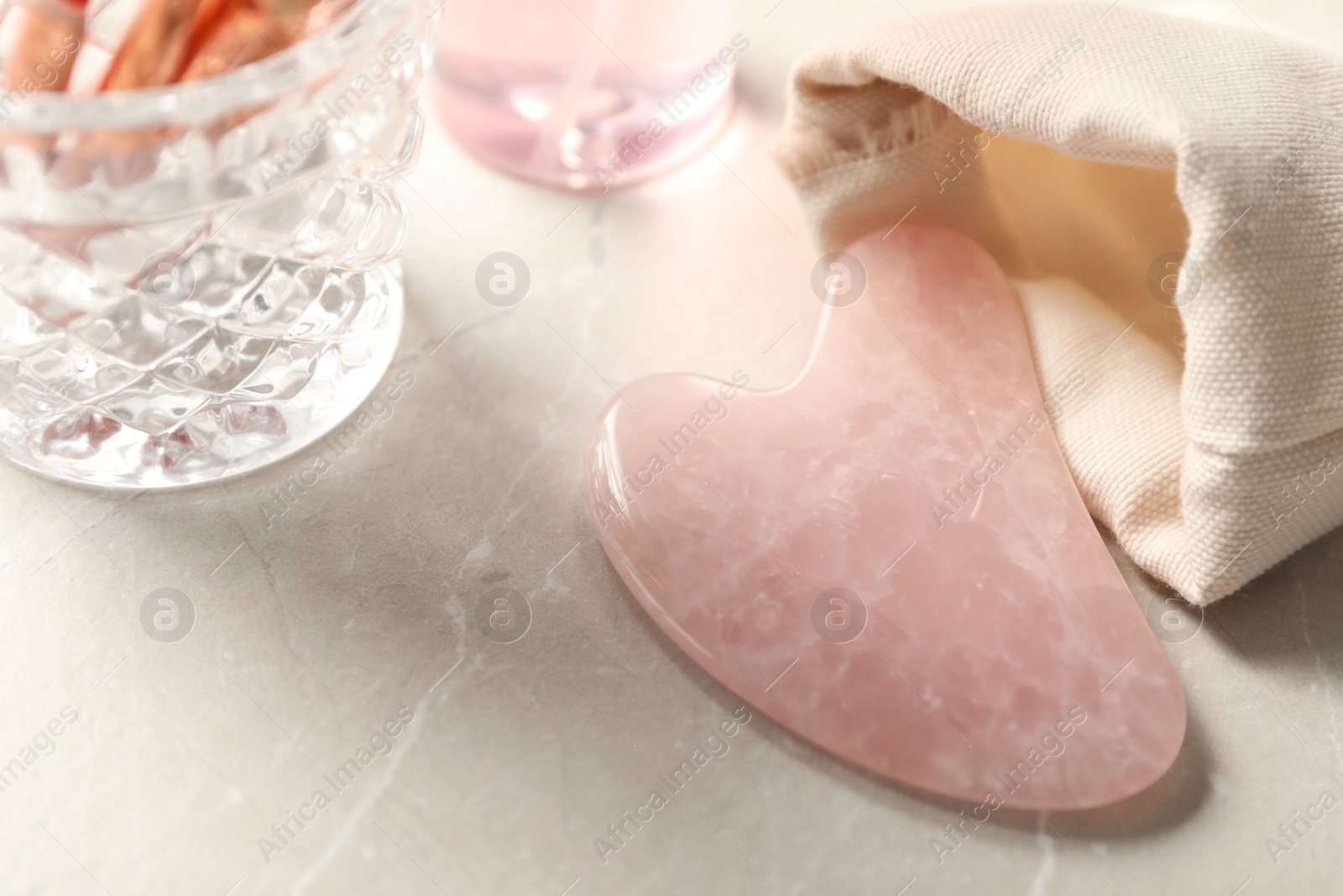 Photo of Rose quartz gua sha tool on light marble table