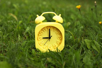 Photo of Yellow alarm clock on green grass outdoors