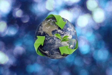 Image of Recycling concept. Earth planet with green arrows and leaves on blurred background, illustration