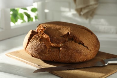 Photo of Freshly baked sourdough bread on white wooden table indoors