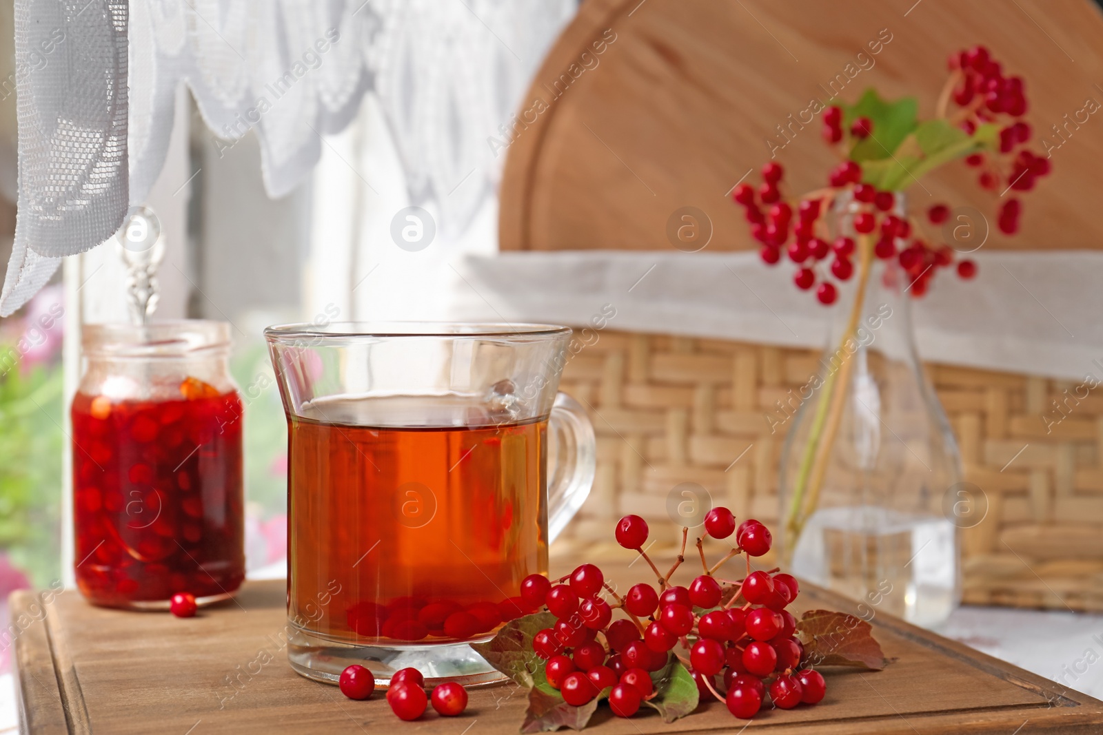 Photo of Helpful viburnum berries and drink on wooden board indoors