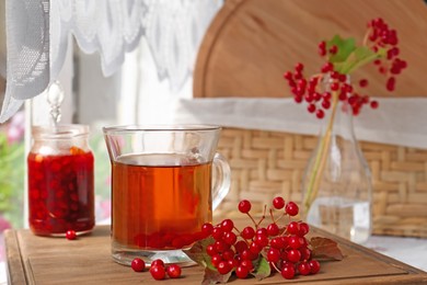 Helpful viburnum berries and drink on wooden board indoors