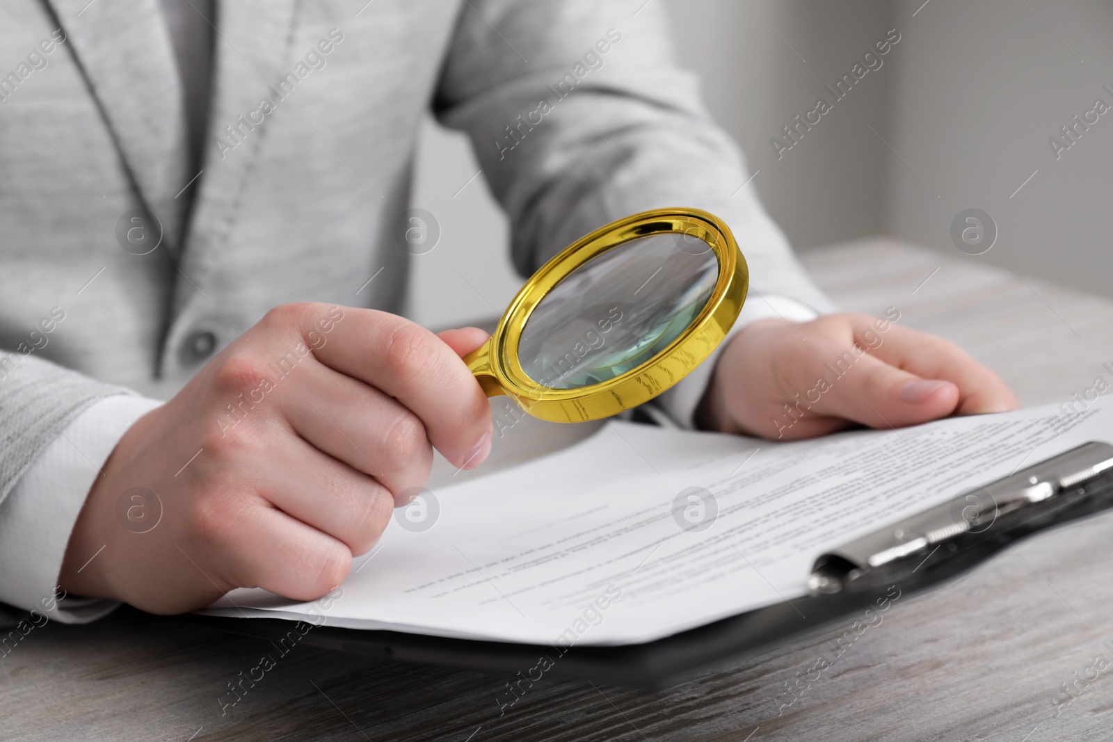 Photo of Man looking at document through magnifier at white wooden table, closeup. Searching concept