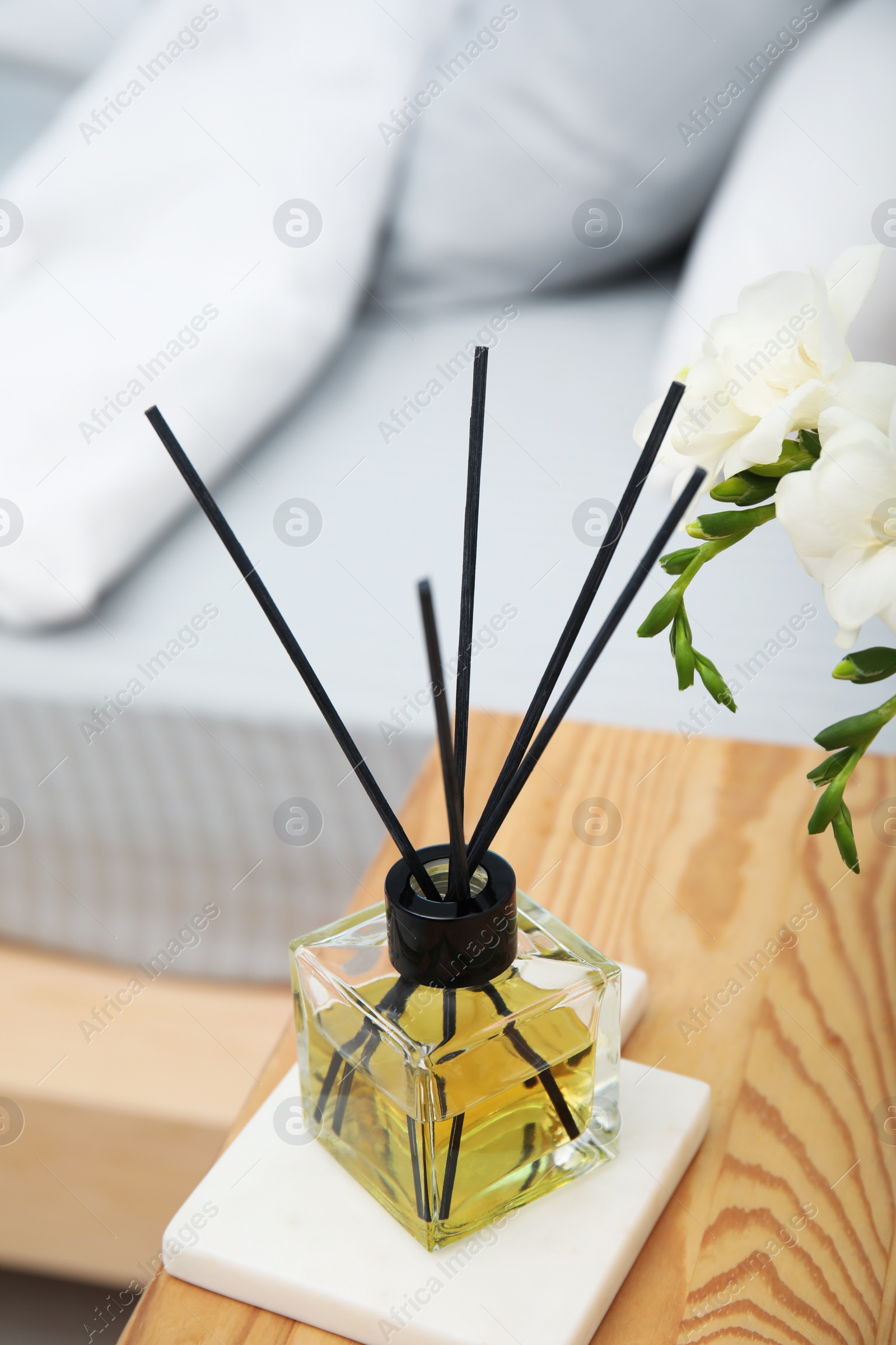 Photo of Reed diffuser on wooden nightstand in bedroom