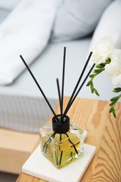 Photo of Reed diffuser on wooden nightstand in bedroom