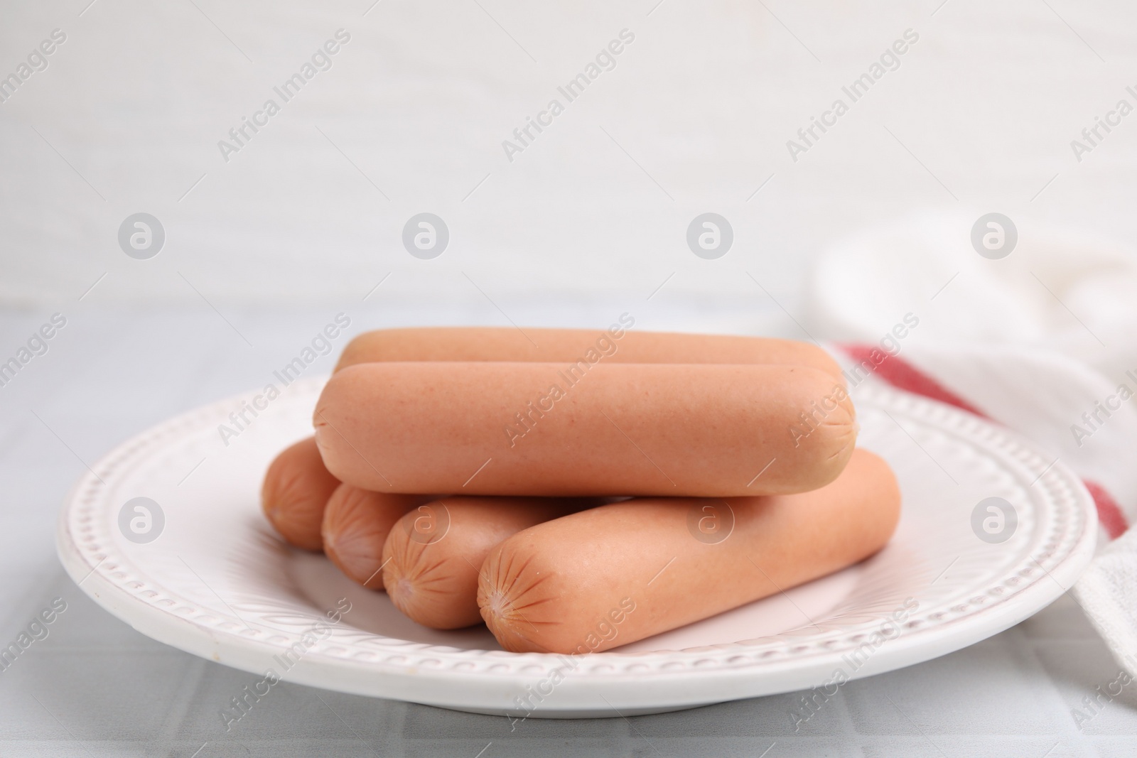 Photo of Delicious boiled sausages on white tiled table, closeup