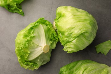 Photo of Fresh green iceberg lettuce heads and leaves on grey table, flat lay