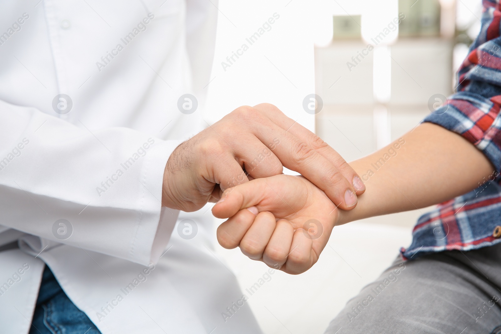 Photo of Doctor checking little boy's pulse with fingers indoors, closeup