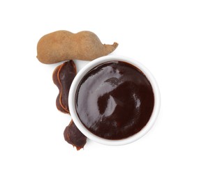 Photo of Bowl of tamarind sauce and fresh pods isolated on white, top view