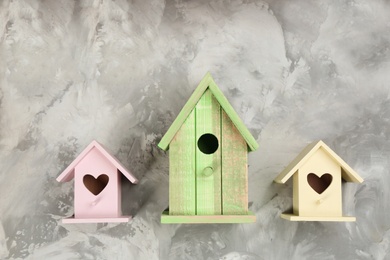 Collection of handmade bird houses on light grey stone background, flat lay