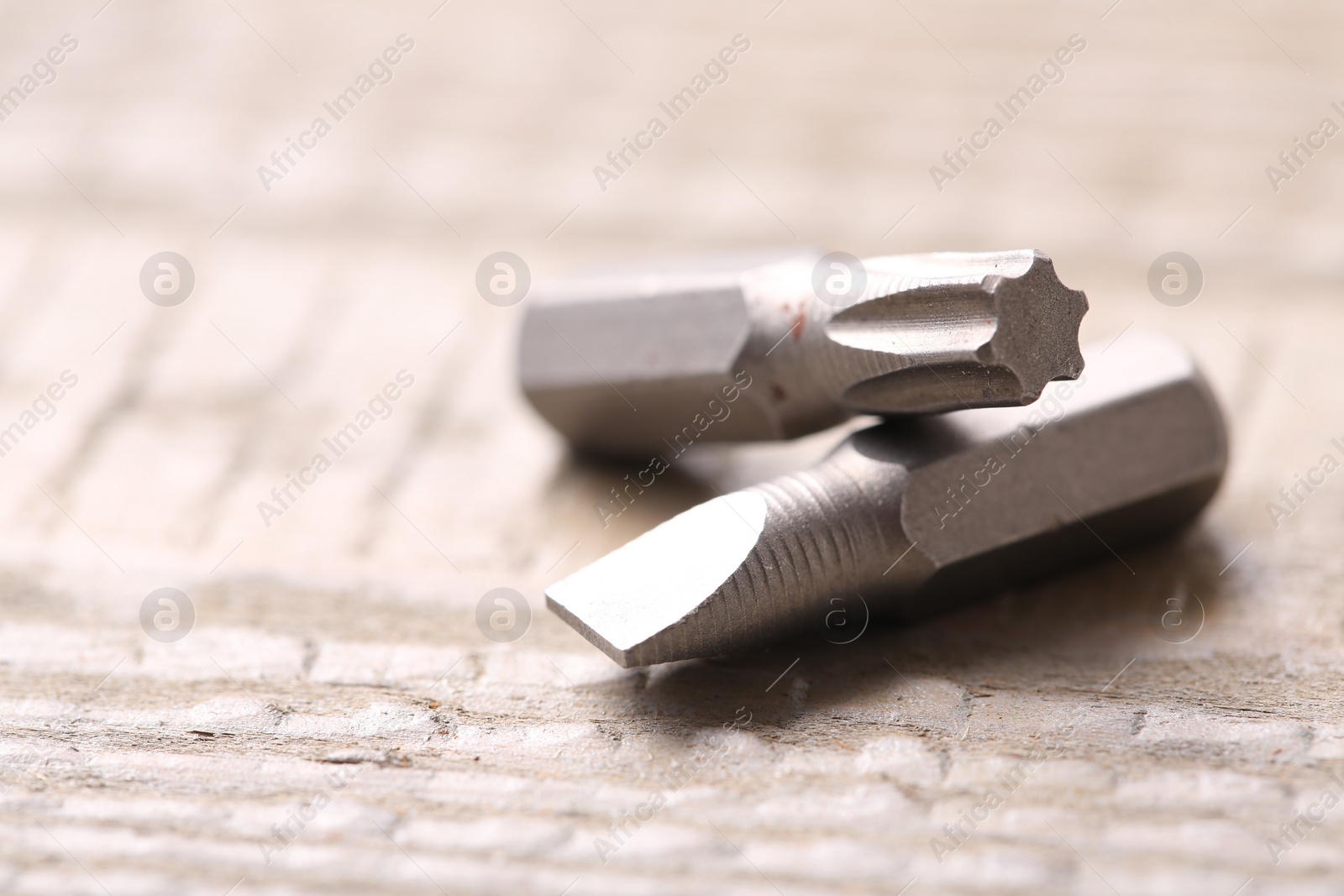 Photo of Different screwdriver bits on wooden table, closeup. Space for text