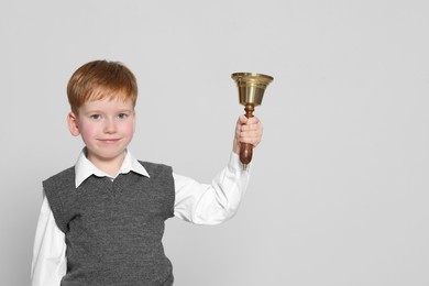 Photo of Pupil with school bell on light grey background. Space for text