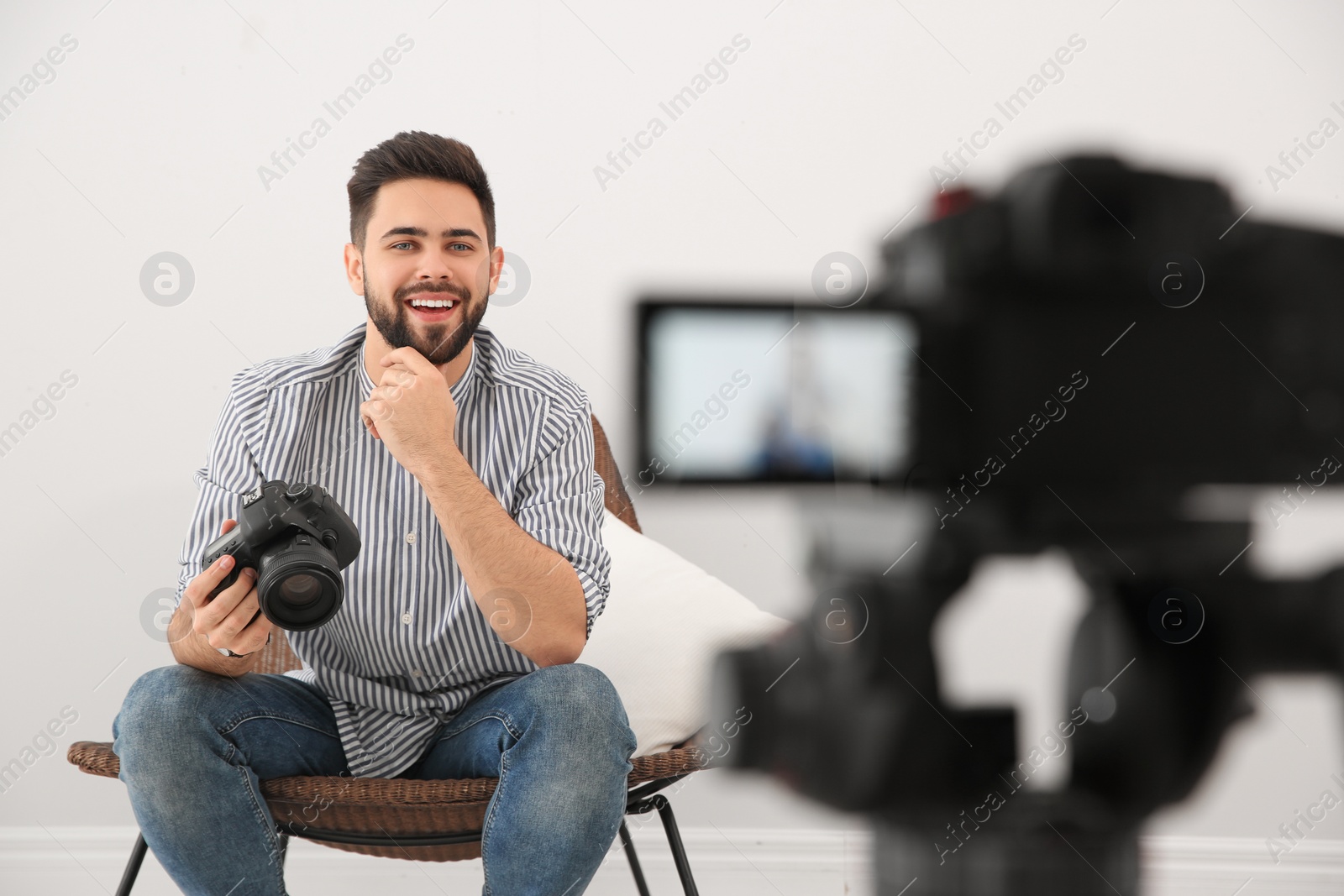 Photo of Young blogger with camera recording video indoors