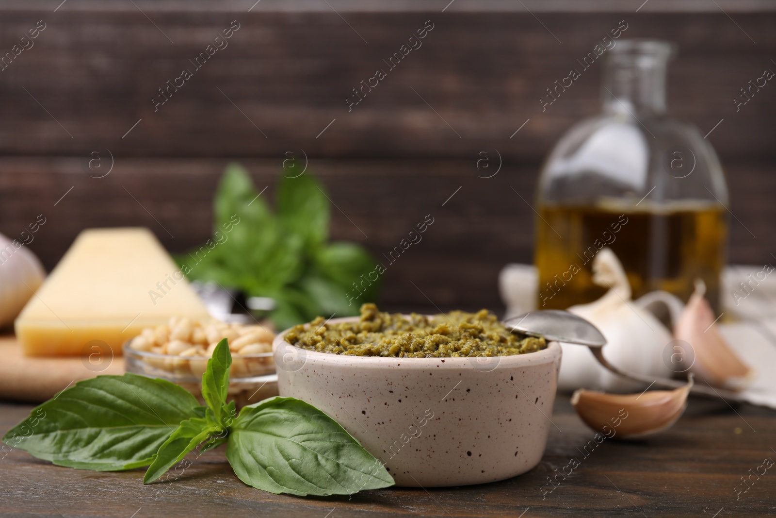 Photo of Tasty pesto sauce and ingredients on wooden table, closeup