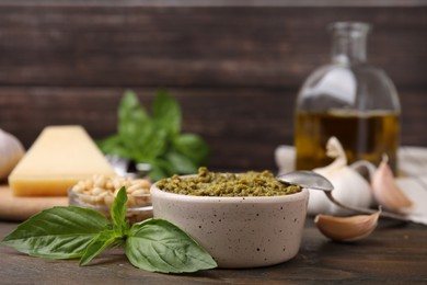 Photo of Tasty pesto sauce and ingredients on wooden table, closeup